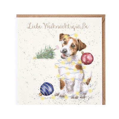 Jack Russell covered in fairy lights and tree baubles and a fallen Christmas tree int he background German Christmas Card